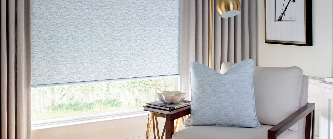 Reading chair next to window with roller shades.